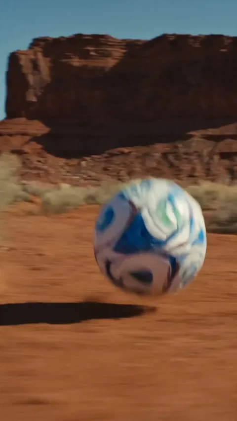 A football bouncing across red desert rock beneath a canyon